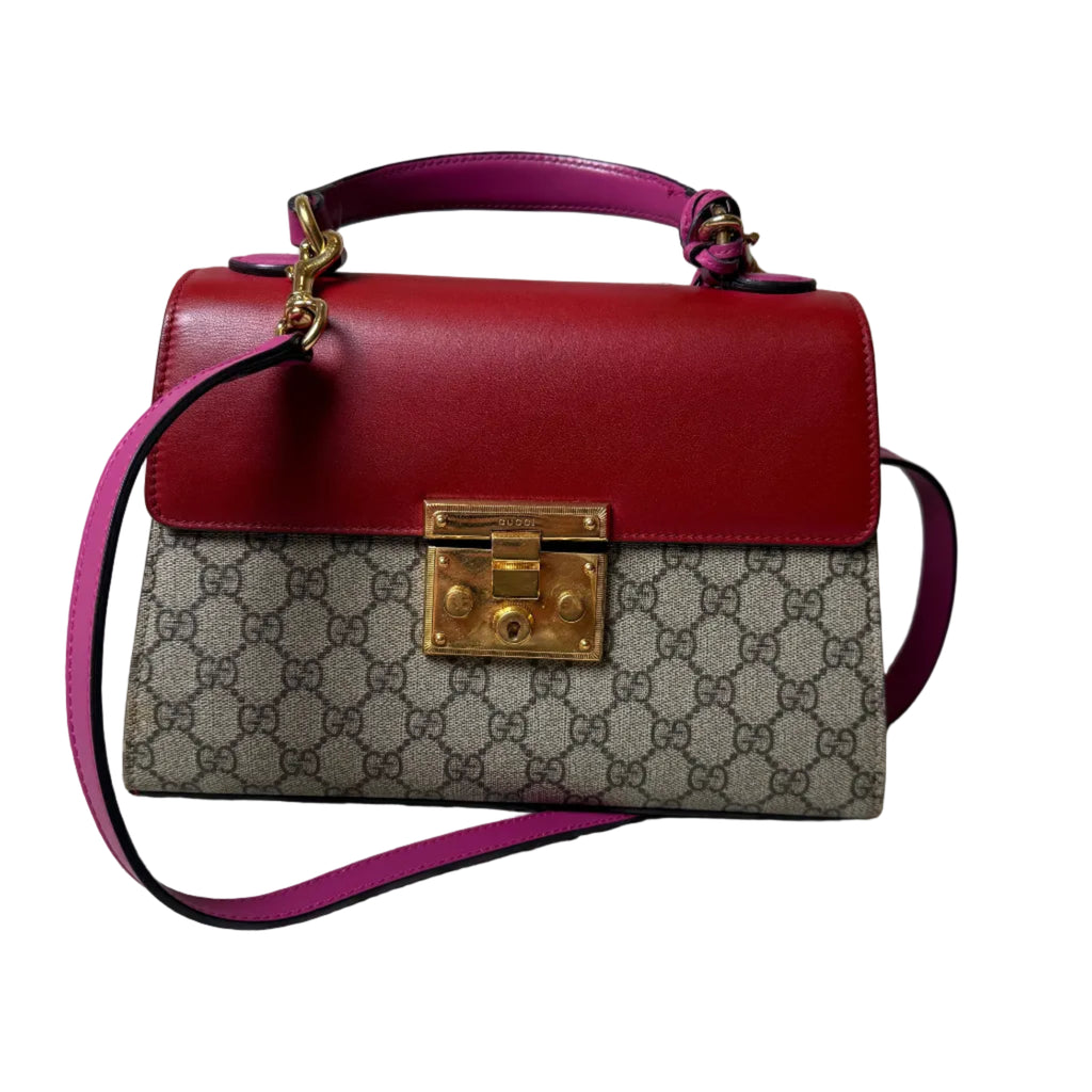 Designer handbag with patterned flap and gold lock on a patterned surface