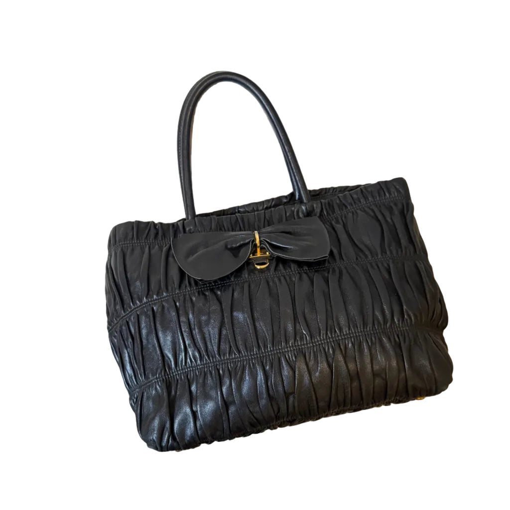 Black leather handbag with a bow detail on a white background