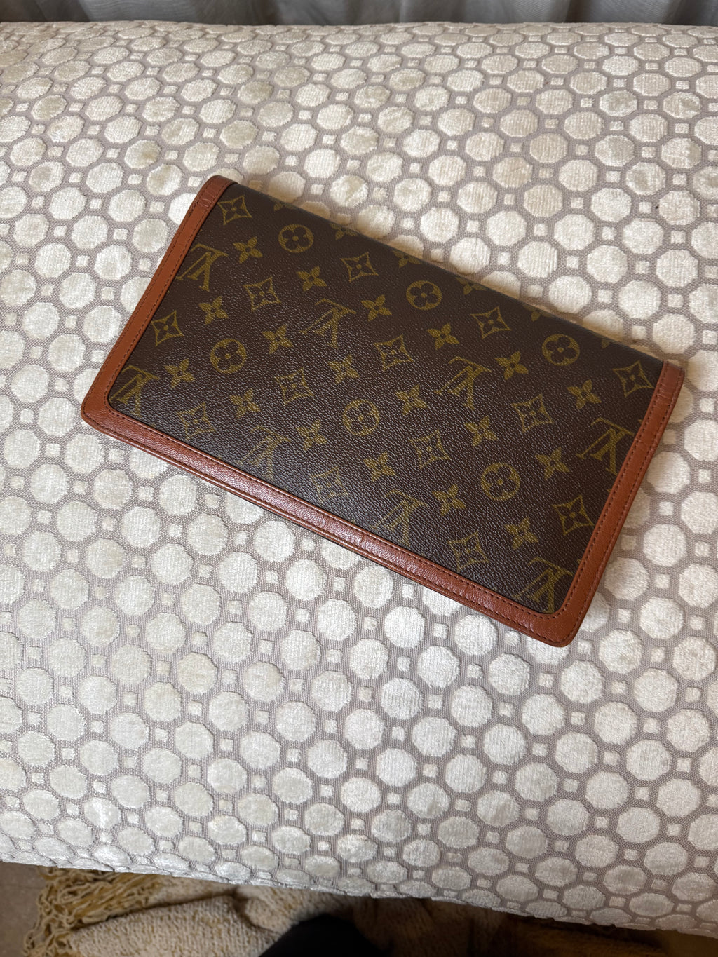 Brown wallet with monogram pattern on a white background