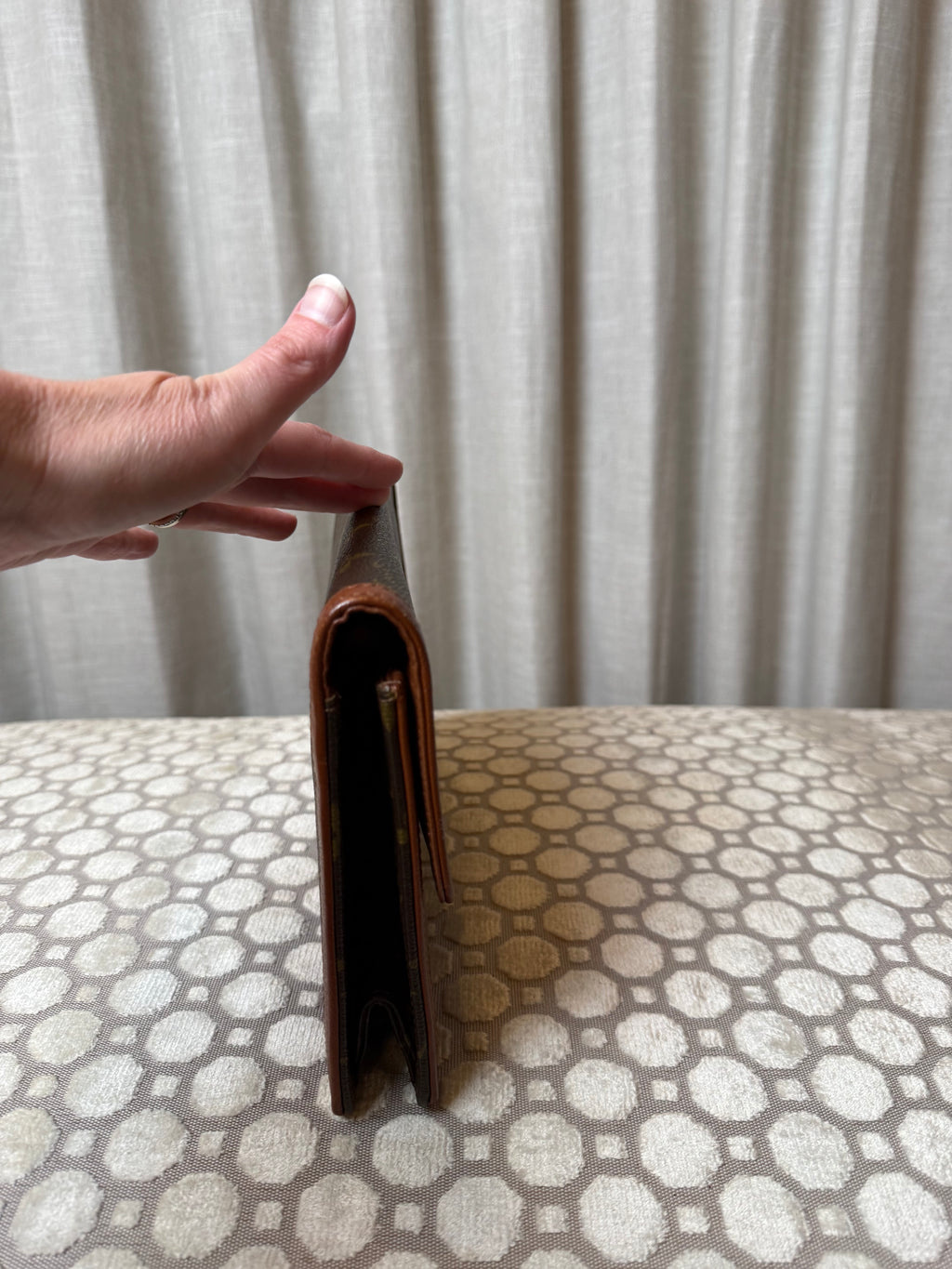 Hand holding a brown leather wallet against a white background