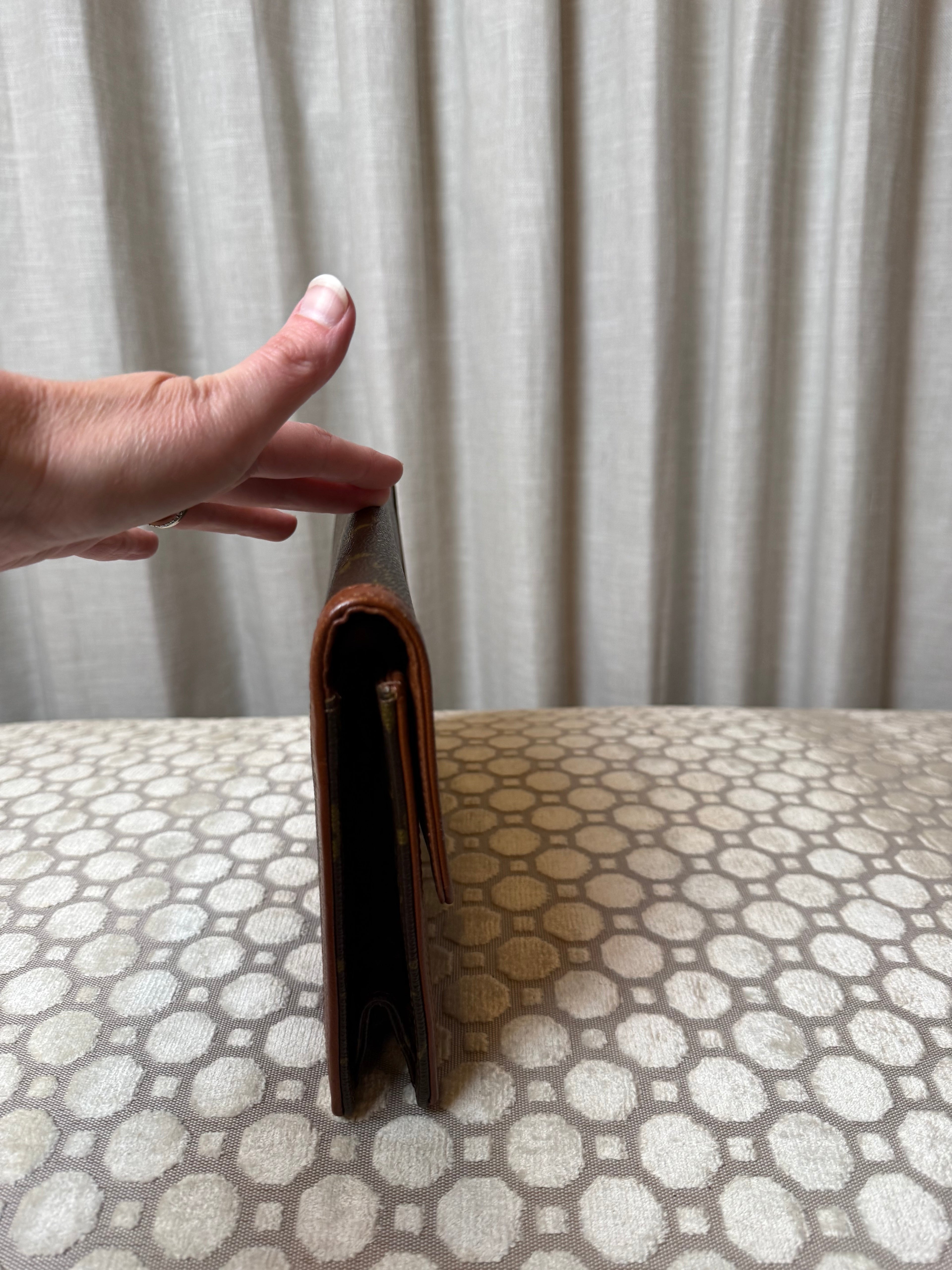 Hand holding a brown leather wallet against a white background